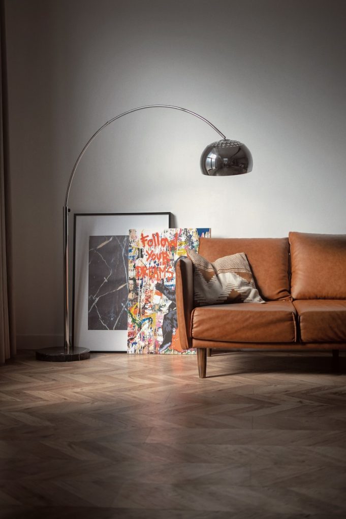 brown wooden framed white padded armchair beside white wall and floor lamp