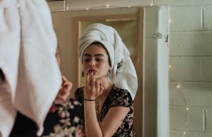 woman putting makeup in front of mirror